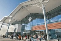 Exteriör av köpcentret Asecs i Jönköping med dess karaktäristiska vita skärmtak och stora glasfasader. Människor rör sig utanför entrén vid en öppen plats i dagsljus. till vänster syns även en del av Coop-butiken.