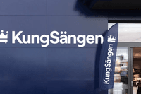En mörkblå butiksfasad med KungSängens vita logotyp och en matchande flagga bredvid en glasentré.