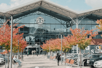 Exteriör av köpcentret Asecs i Jönköping under en solig höstdag, med färgstarka träd framför huvudentrén och parkerade bilar i förgrunden.