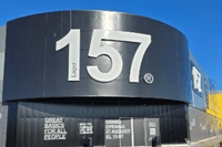 Exteriör av en Lager 157-butik i svarta metallplåtar med stor vit logotyp och information om nyöppning.