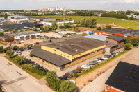 Flygfoto över ett industriområde med kommersiella fastigheter, lagerlokaler och parkerade bilar.