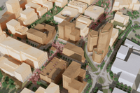 Tre personer i arbetskläder och skyddshjälmar står vid ett bord i en industrilokal eller verkstad. De tittar tillsammans på en surfplatta och diskuterar ett arbete, med verktyg och maskiner synliga i den suddiga bakgrunden.