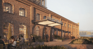 Digital rendering (3D-bild) av fasaden på "Munksjöstaden Hotell", som är inrymd i en gammal industribyggnad i rött tegel med stora rundbågade fönster. Entrén har en modern baldakin täckt med lampor och framför byggnaden finns en uteservering i gulgrönt oc