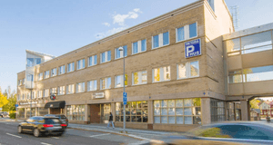 Exteriör av Viktoria P-hus, en flervåningsbyggnad i gult tegel med en inglasad gångbro, belägen vid en gata med passerande bilar.