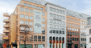 En modern kontorsbyggnad i Göteborg med en ljus fasad, stora fönsterpartier och en stor banner med texten "Kontor i Göteborgs bästa läge?".