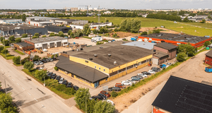 Flygfoto över ett industriområde med kommersiella fastigheter, lagerlokaler och parkerade bilar.
