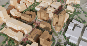 Tre personer i arbetskläder och skyddshjälmar står vid ett bord i en industrilokal eller verkstad. De tittar tillsammans på en surfplatta och diskuterar ett arbete, med verktyg och maskiner synliga i den suddiga bakgrunden.