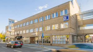 Exteriör av Viktoria P-hus, en flervåningsbyggnad i gult tegel med en inglasad gångbro, belägen vid en gata med passerande bilar.