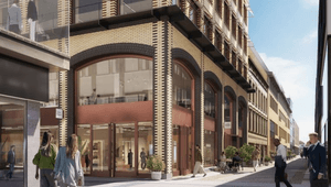 En digital visualisering av en modern stadsgata med en stor tegelbyggnad i fokus. Byggnaden har karaktäristiska rundade valv med stora glaspartier och butiker i gatuplan. Människor promenerar längs den ljusa gågatan och sitter på uteserveringar i solljuse