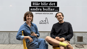 Två leende personer framför en skylt för Bruket kaffebar med texten 'Här blir det andra bullar... öppnar hösten 2026'.