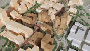 Tre personer i arbetskläder och skyddshjälmar står vid ett bord i en industrilokal eller verkstad. De tittar tillsammans på en surfplatta och diskuterar ett arbete, med verktyg och maskiner synliga i den suddiga bakgrunden.