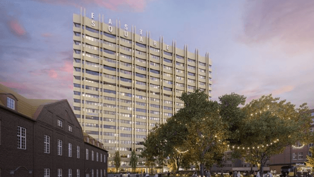 Bilden är en kvälls- eller skymningsrendering som visar en hög, modern byggnad med en distinkt och iögonfallande arkitektur. Byggnaden är ett flervåningshus, troligen ett bostads- eller hotellkomplex, med en fasad i en sandfärgad eller ljust guldton. Fasa