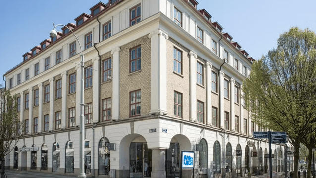 Bottenvåningen är utformad med en imponerande arkad av breda, rundade valv som ger plats åt butikslokaler och entréer. Ovanför detta syns flera enhetliga våningar med rektangulära fönster, som har mörkröda eller rödbruna karmar. Byggnadens hörn är markera