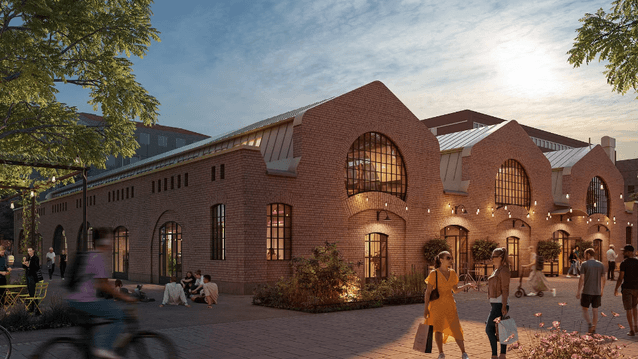 En vy av en tegelbyggnad i industriell stil med stora halvmåneformade fönster på andra våningen. Utanför rör sig människor.