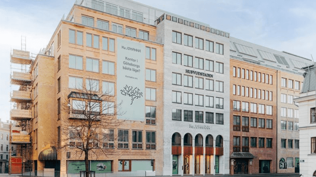 En modern kontorsbyggnad i Göteborg med en ljus fasad, stora fönsterpartier och en stor banner med texten "Kontor i Göteborgs bästa läge?".