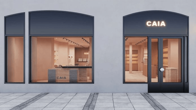 Butiksfasad i minimalistisk stil för CAIA Cosmetics med mörka fönsterramar och varmt rosa belyst interiör.