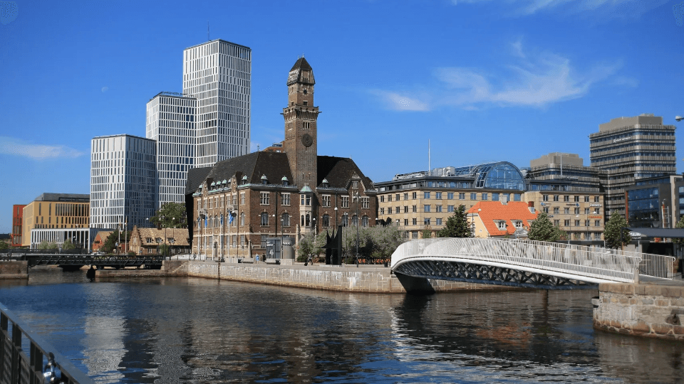 Stadslandskap vid kanalen i Malmö med gamla Posthuset, en gångbro och moderna skyskrapor.