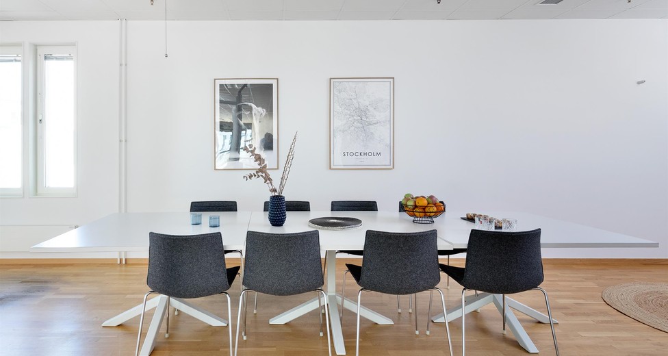 Mötesrum med vita väggar och trägolv.