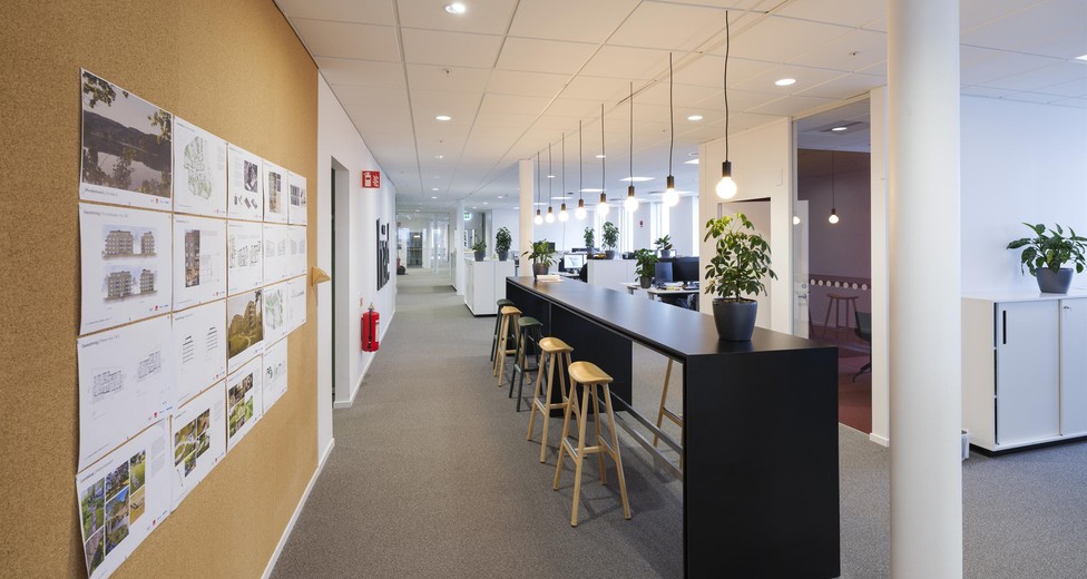 Sittplatser vid barbord och anslagstavla i kontorslandskapet.